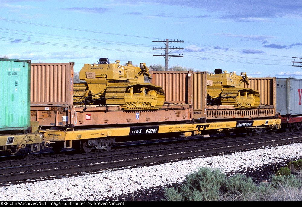 Trailer Train flat TTWX #978702 loaded with bulkhaed containers carrying Komatsu 65P bulldozers.